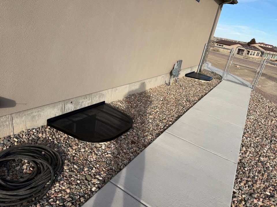 Black custom window well cover beside backyard sidewalk