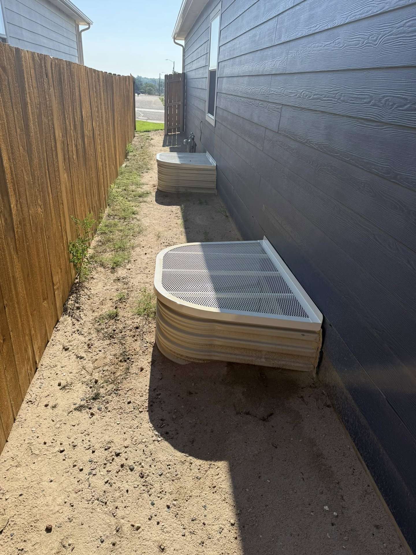 Row of light-colored window wells covered along side yard